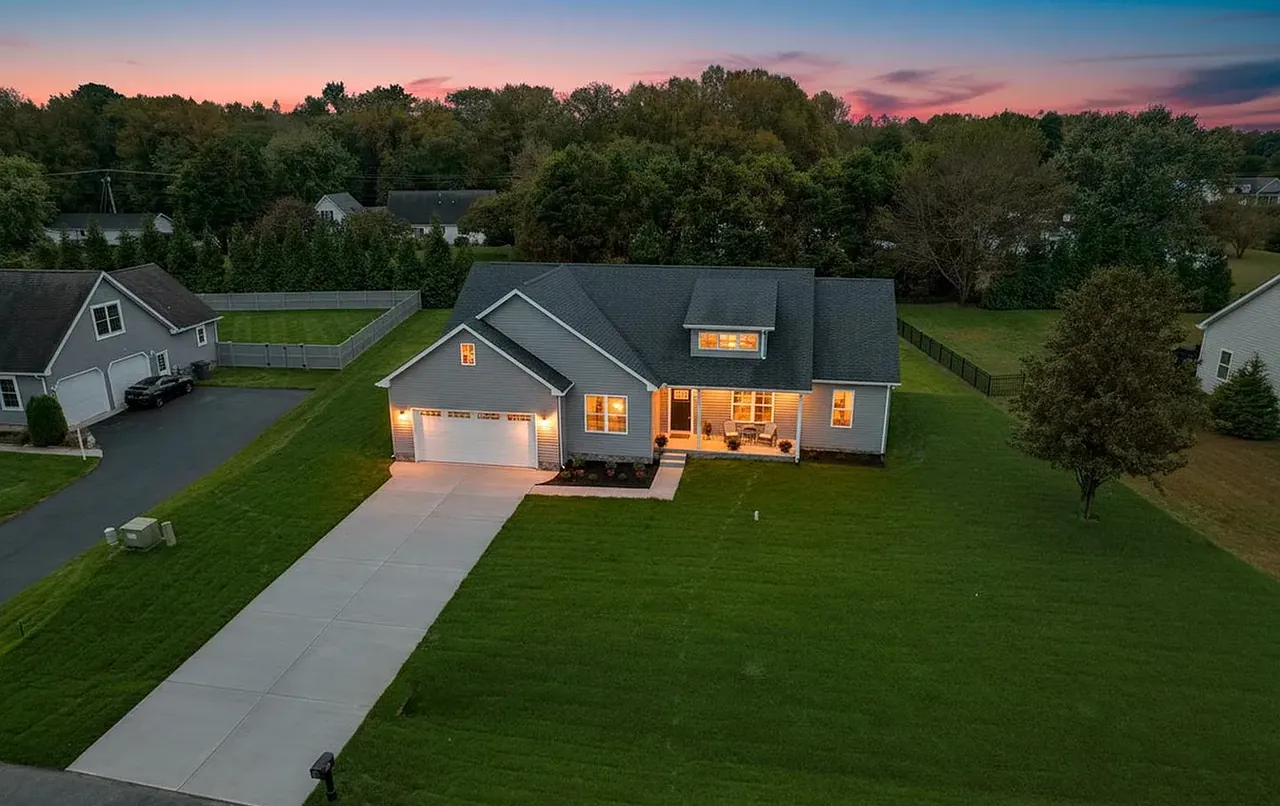 A Legacy Home Builders custom home at dusk, windows warmly lit, on a landscaped Delaware lot
