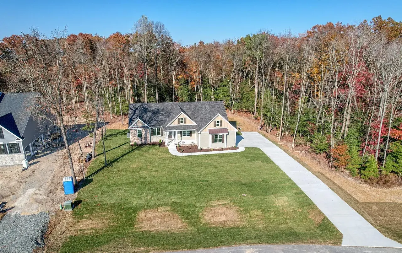 Aerial view of a finished home on a wooded lot in autumn